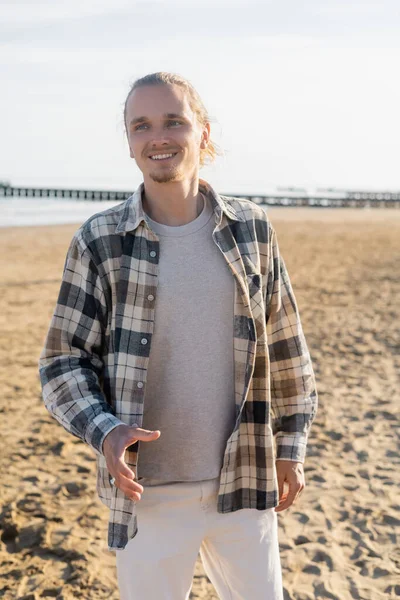 Cheerful man in checkered shirt standing on beach in Italy — Stock Photo