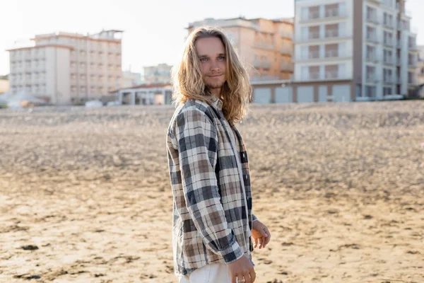 Hombre de pelo largo de pie en la playa en Italia - foto de stock