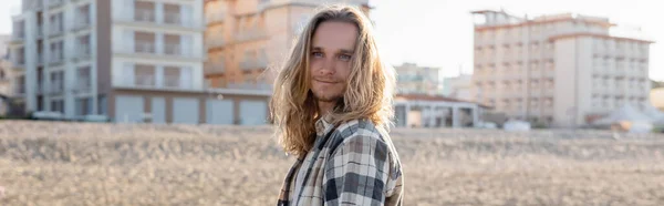 Jeune homme aux cheveux longs debout sur la plage en Italie, bannière — Photo de stock