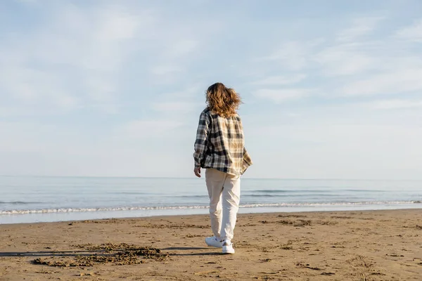 Visão traseira do homem de cabelos longos andando na praia perto do mar adriático na Itália — Fotografia de Stock