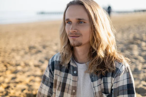 Homme aux cheveux longs regardant loin sur la plage à Trévise — Photo de stock