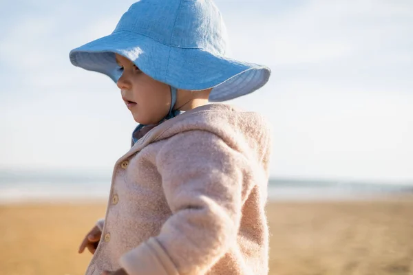 Baby Mädchen mit Panamahut steht am verschwommenen Strand — Stockfoto