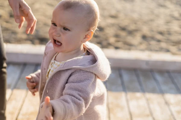 Upset baby girl standing near father on beach — Stock Photo