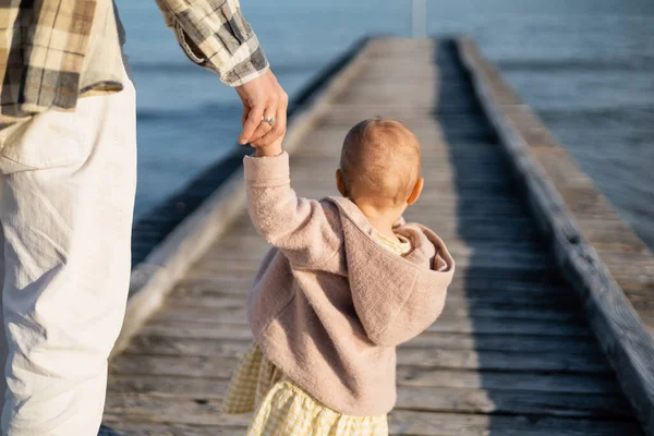 Back view of toddler girl holding hand of father on pier on beach in Treviso — Stock Photo