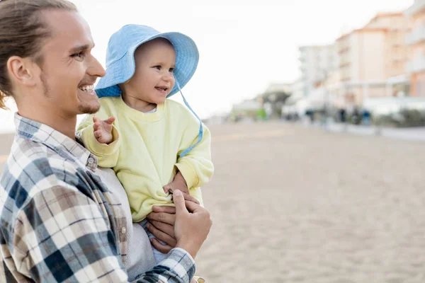 Sorrindo pai e bebê menina olhando para longe na praia na Itália — Fotografia de Stock