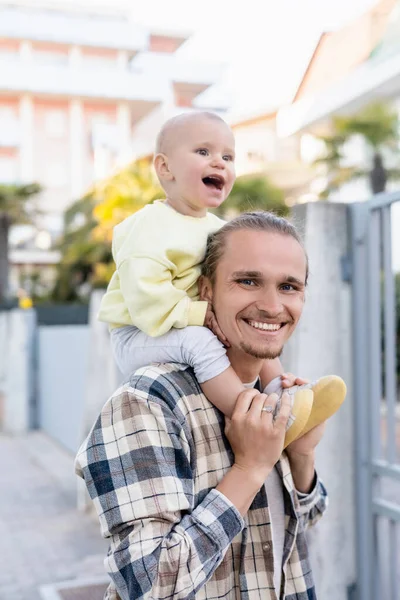 Positive father holding cheerful daughter on shoulders on urban street in Treviso — Stock Photo
