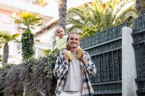 Smiling man carrying baby on shoulders on urban street in Treviso — Stock Photo