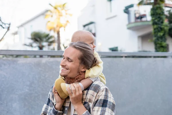 Cheerful young dad holding daughter on shoulders on urban street in Treviso — Stock Photo