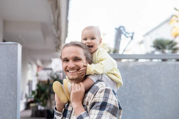 Счастливый ребенок и отец смотрят в камеру на городской улице — стоковое фото