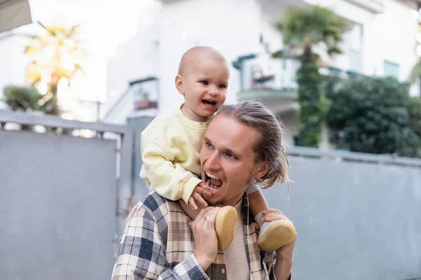 Father holding baby on shoulders on urban street — Stock Photo