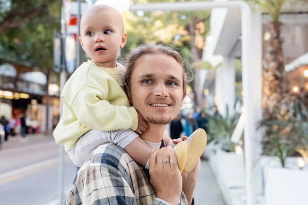 Smiling father holding child on shoulders on urban street in Treviso — Stock Photo