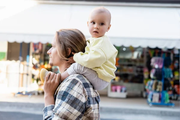 Man carrying baby daughter on shoulders on urban street in Treviso — Stock Photo