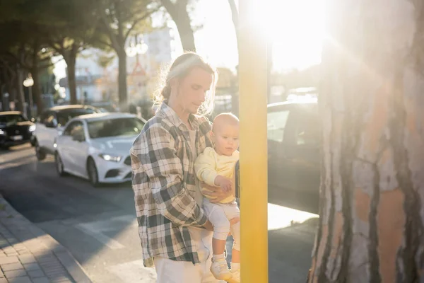 Father holding baby daughter near traffic light and road on urban street in Treviso — Stock Photo
