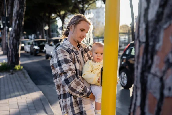 Young man holding baby girl near road on urban street in Treviso — Stock Photo