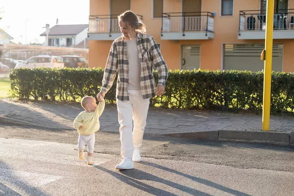 Улыбающийся отец и дочь малыша идут по пешеходной дорожке по городской улице в Тревизо — стоковое фото