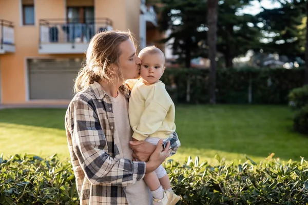 Long haired dad kissing baby daughter on urban street in Treviso — Stock Photo