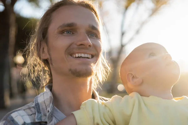 Cheerful man looking away near baby girl outdoors — Stock Photo