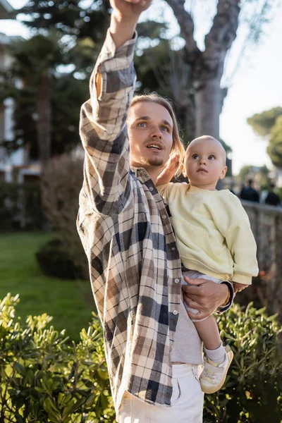 Мужчина смотрит в сторону, держа дочку на улице в Тревизо — стоковое фото