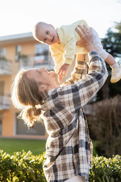 Positive man playing with baby daughter on urban street in Treviso — Stock Photo