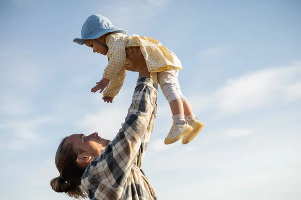 Seitenansicht junger Vater hält Kleinkind-Tochter mit Himmel im Hintergrund — Stockfoto