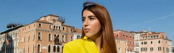 Young redhead woman looking away near venetian buildings on background, banner — Stock Photo