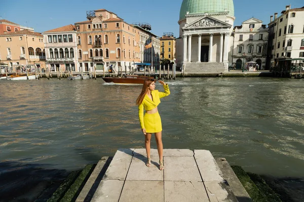 Frau in gelber Kleidung blickt auf Pier in der Nähe des Canal Grande in Venedig weg — Stockfoto