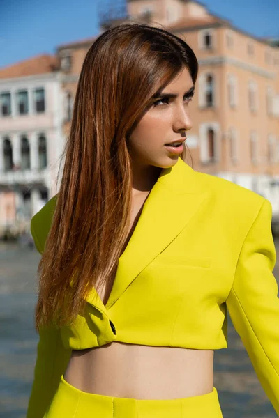 Рыжая женщина в желтой куртке смотрит в сторону на размытом фоне в Венеции — стоковое фото