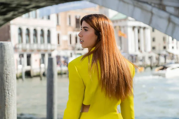 Rossa donna in abiti gialli alla moda guardando lontano a Venezia su sfondo sfocato — Foto stock