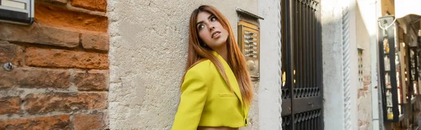 Руденька жінка у жовтій куртці, що висить біля стіни на вулиці у Венеції. — стокове фото