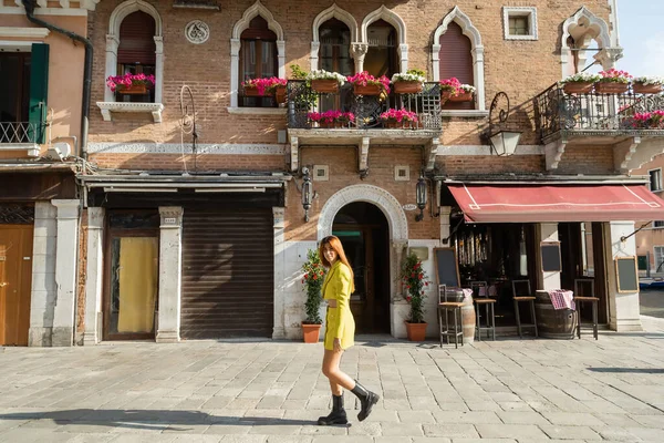 Longitud completa de la mujer en ropa elegante caminando por la calle en Venecia - foto de stock