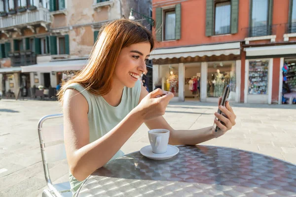 Heureuse rousse femme regardant téléphone mobile sur la terrasse du café à Venise — Photo de stock