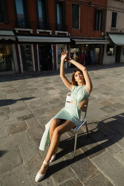 Piena lunghezza di donna in abito elegante seduta sulla sedia in strada a Venezia — Foto stock