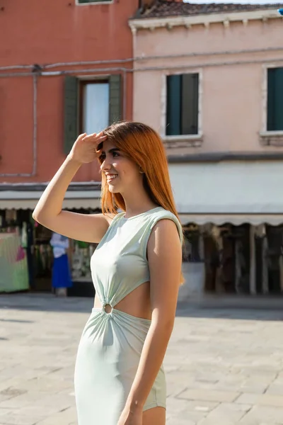 Rothaarige Frau mit der Hand über den Augen, die in Venedig lächelt und wegschaut — Stockfoto