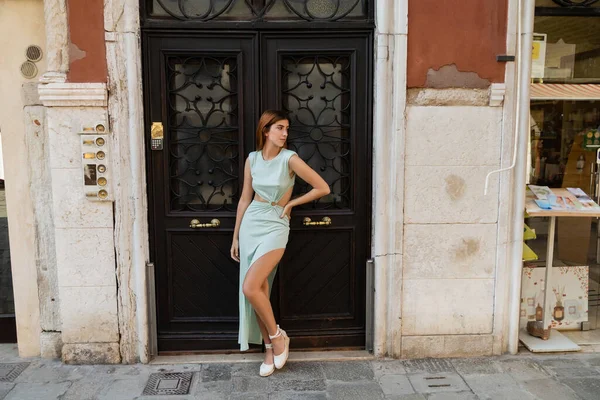 Piena lunghezza di donna alla moda con mano sul fianco vicino edificio veneziano medievale — Foto stock