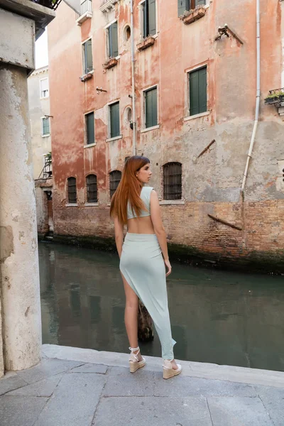 Pleine longueur de femme en robe élégante debout près du canal sur la rue vénitienne — Photo de stock