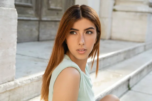 Jeune femme aux cheveux roux regardant loin sur la rue floue à Venise — Photo de stock