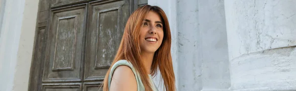 Heureuse jeune femme aux cheveux roux souriant près du bâtiment à Venise, bannière — Photo de stock