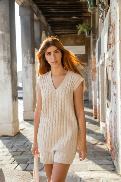 Redhead woman in knitwear looking at camera near colonnade in Venice — Stock Photo