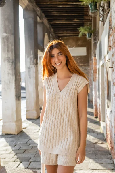 Positive woman with red hair smiling at camera on street in Venice — Stock Photo