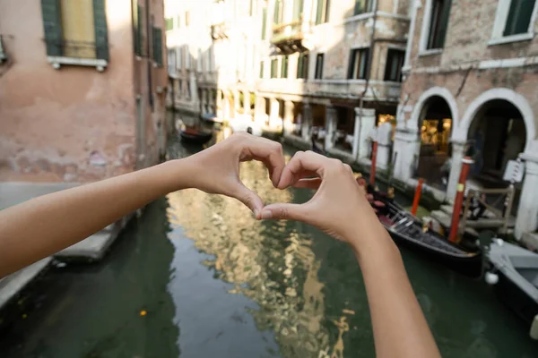 Cropped view of tourist showing heart sign on blurred street in Venice — Stock Photo