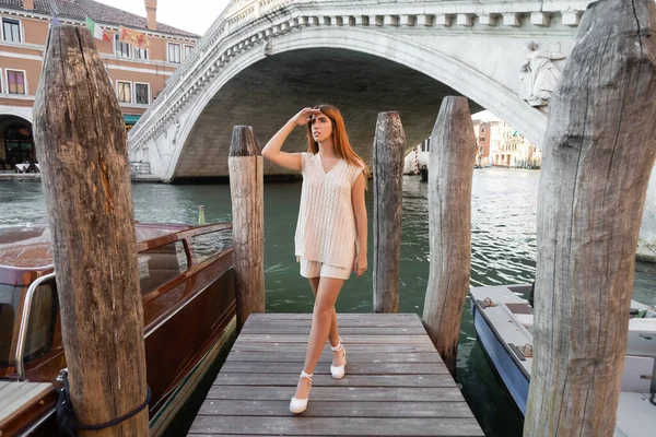 Toute la longueur de la femme regardant loin sur la jetée près des pilotis en bois sur le Grand Canal vénitien — Photo de stock