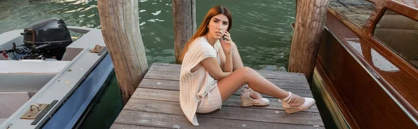 High angle view of young woman sitting on wooden pier near motor boats in Venice, banner — Stock Photo