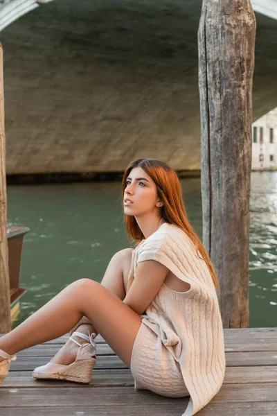 Verträumte rothaarige Frau sitzt auf Seebrücke in Venedig und schaut weg — Stockfoto