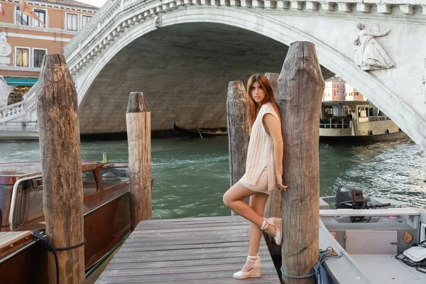 Frau in sommerlicher Strickkleidung und Keilsandalen posiert in der Nähe von Holzstapeln in Venedig — Stockfoto