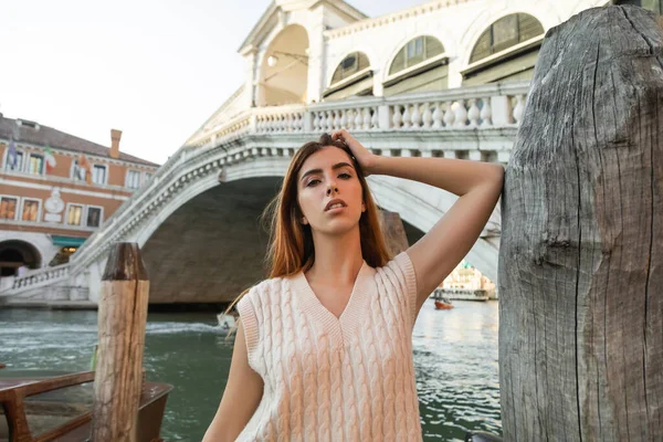 Mulher ruiva olhando para a câmera perto de empilhamento de madeira e Ponte Rialto em Veneza — Fotografia de Stock