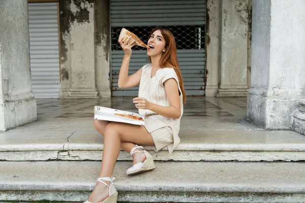 Pleased woman eating pizza in Venice while sitting on stairs outdoors — Stock Photo