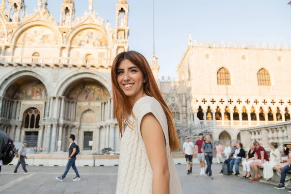 ITALIA, VENECIA - 12 DE MAYO DE 2022: pelirroja feliz mirando a la cámara en la plaza de San Marcos en Venecia - foto de stock