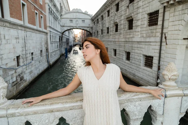 Рудоволоса жінка, що дивиться у далечінь біля мосту Сігс на задньому плані у Венеції. — стокове фото
