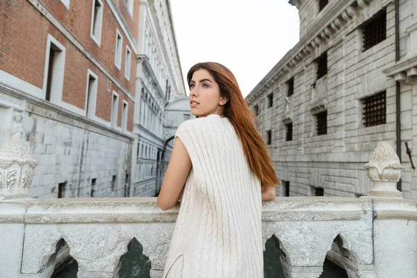 Redhead woman in sleeveless jumper standing on bridge near medieval prison in Venice — Stock Photo