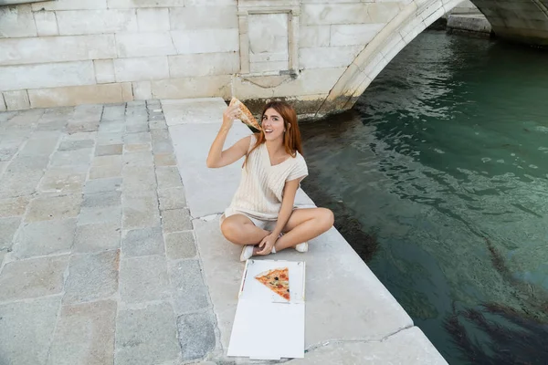 Високий кут зору щасливої жінки, яка насолоджується піцою під час відпустки в Італії. — стокове фото